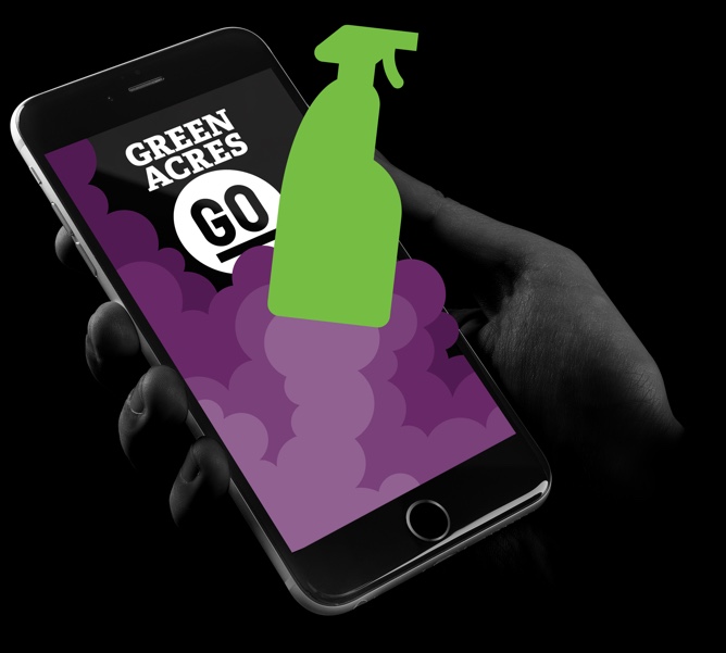A persons hand holding an iphone with the Green Acres Go app open. An image of a bottle of cleaning product is blasting off like a rocket is visible on the phone.